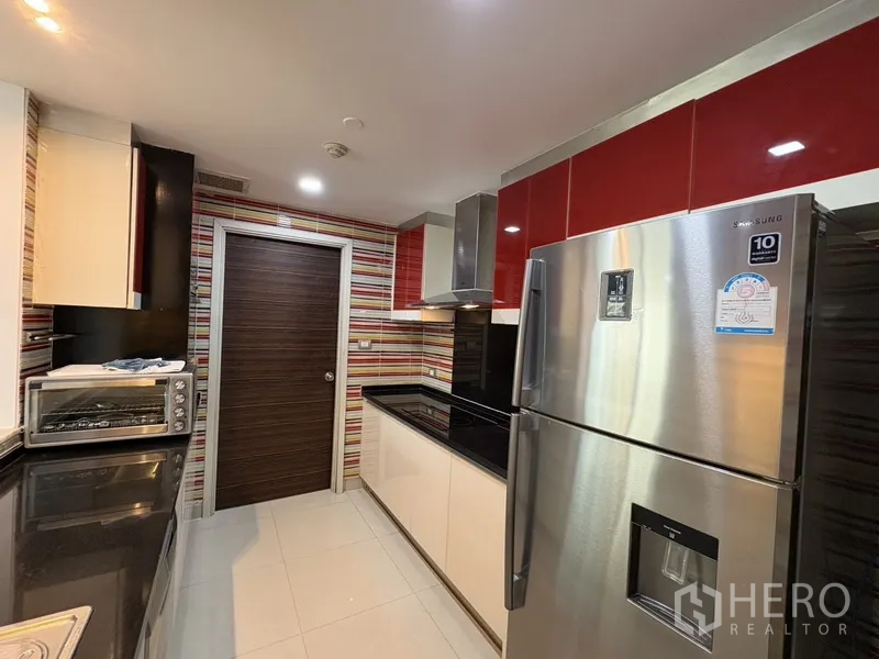 คอนโด for rent in Khlong San, Bangkok - ครัวสไตล์โมเดิร์น ตู้ลอยสีแดง ผนังลายสลับ เคาน์เตอร์สีดำ และตู้เย็นสแตนเลส