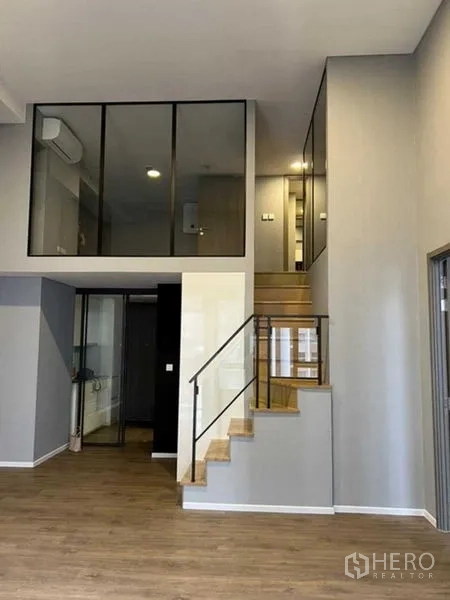 Condominium for sale in Huai Khwang, Bangkok - Living room with staircase, mezzanine glass partitions and high ceiling.