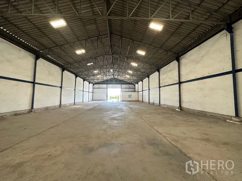 Warehouse for rent in Bang Bo, Samut Prakan - Long open warehouse bay with high ceiling, concrete slab, and large shutter at the far end.