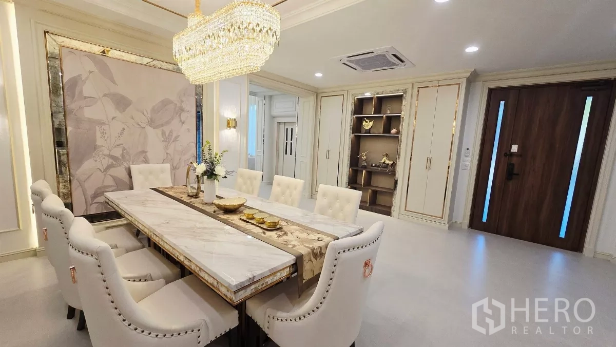Detached House for rent in Prawet, Bangkok - Dining area with crystal pendant lighting, built-in shelving and a wood front door.