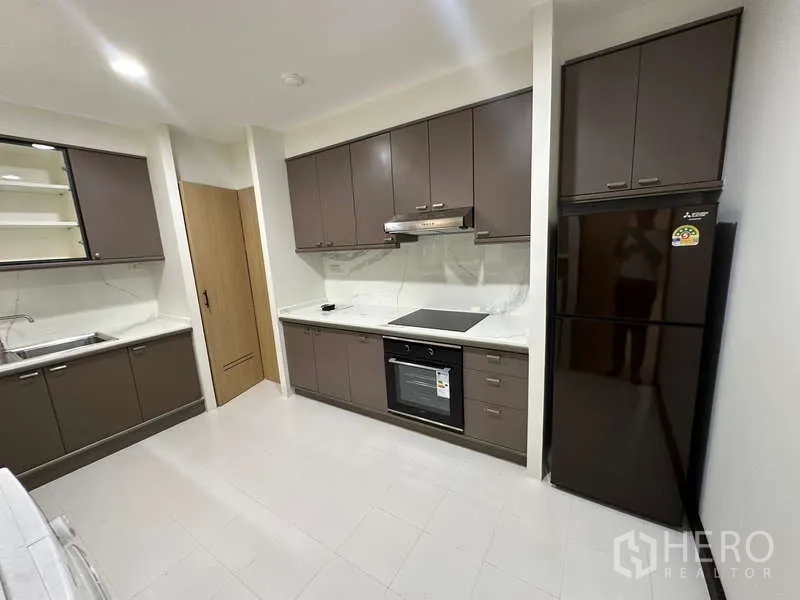 คอนโด ให้เช่าในWatthana, Bangkok - ครัวปิดตู้สีน้ำตาล เตาไฟฟ้า เตาอบ และตู้เย็นขนาดใหญ่