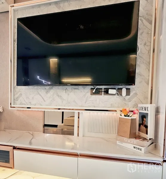 Condominium for sale in Bang Rak, Bangkok - Feature TV wall with large flat-screen above a marble console and decor.