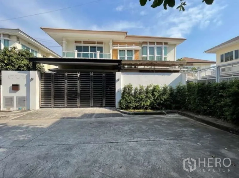 Detached House for rent in Bang Phli, Samut Prakan - Front facade with gated driveway, covered carport and modern windows.
