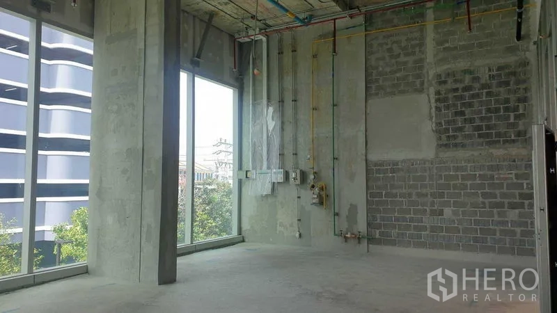 零售空间 出租 - 零售毛坯角落，裸露管线、挑高空间与高窗。