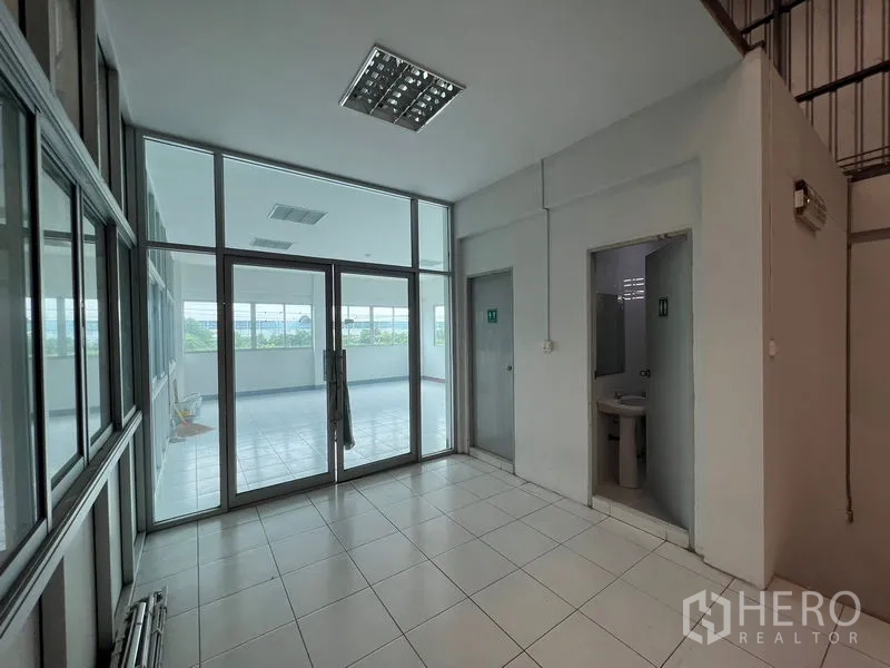 Warehouse for rent in Lat Krabang, Bangkok - Office core with tiled floors, glass partitions, restrooms, and access to a balcony area.