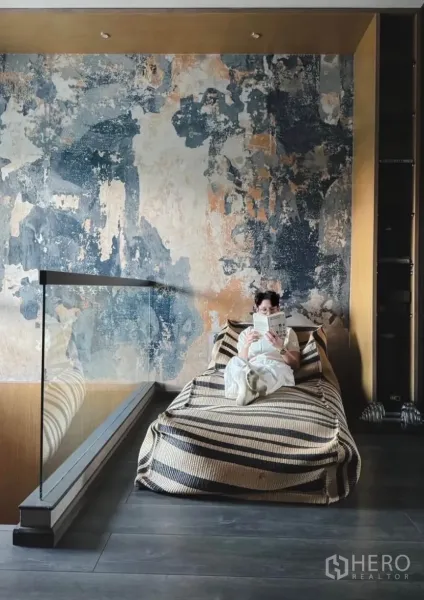 Townhouse for rent or sale in Bang Phli, Samut Prakan - Loft-style reading nook with a textured feature wall, striped daybed and glass railing.