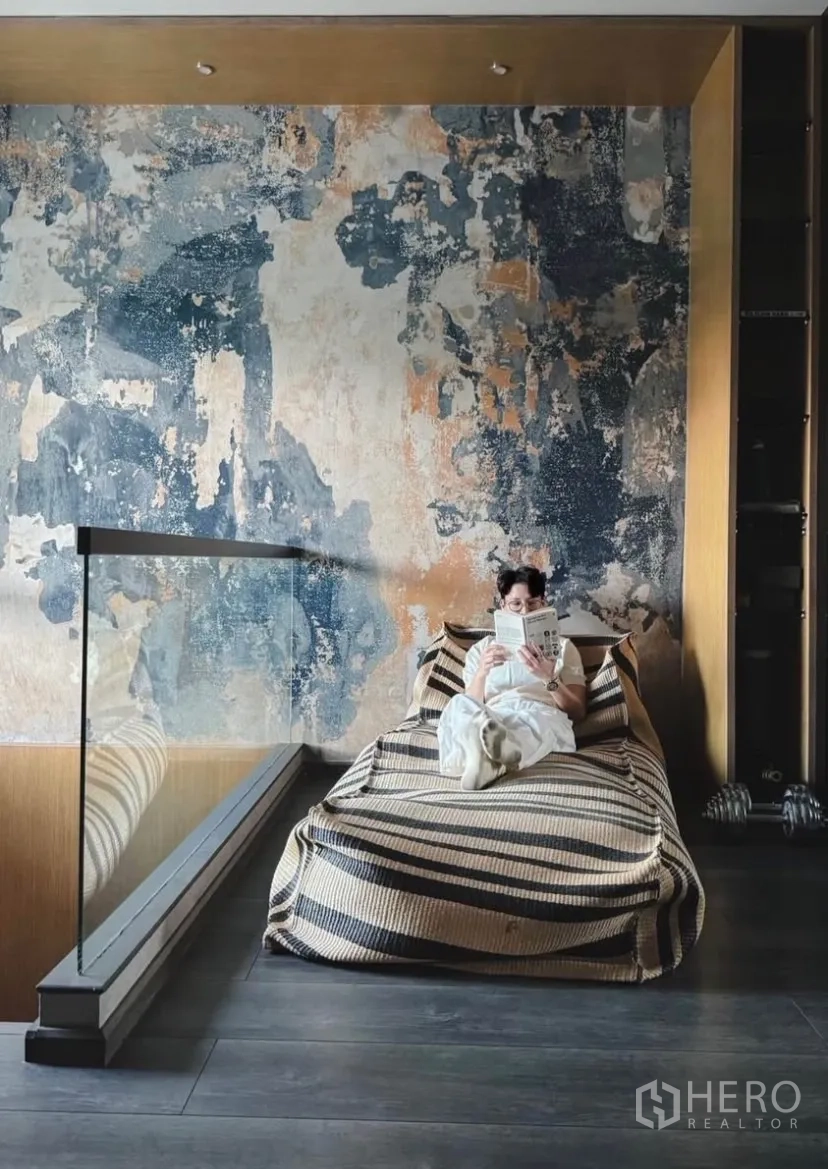 Townhouse for rent or sale in Bang Phli, Samut Prakan - Loft-style reading nook with a textured feature wall, striped daybed and glass railing.