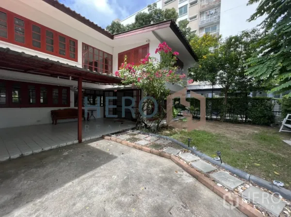 独立式住宅 出租在Watthana, Bangkok - 庭院一角，九重葛、铺装车道及邻近中高层建筑