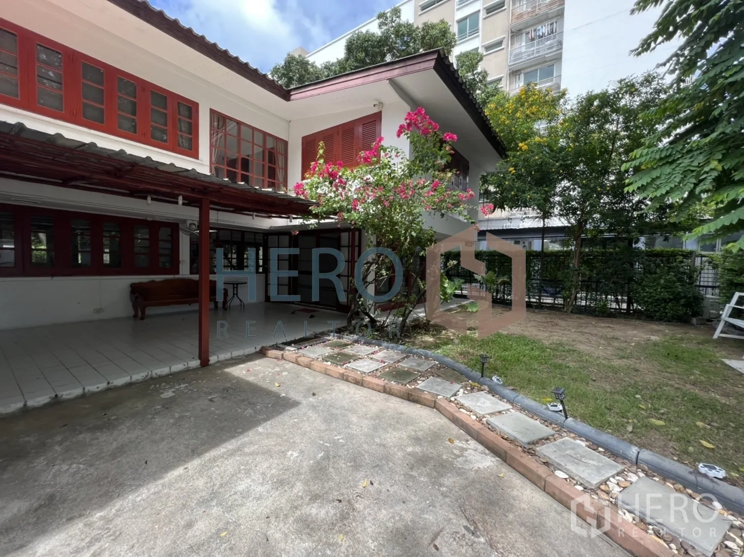 独立式住宅 出租在Watthana, Bangkok - 庭院一角，九重葛、铺装车道及邻近中高层建筑