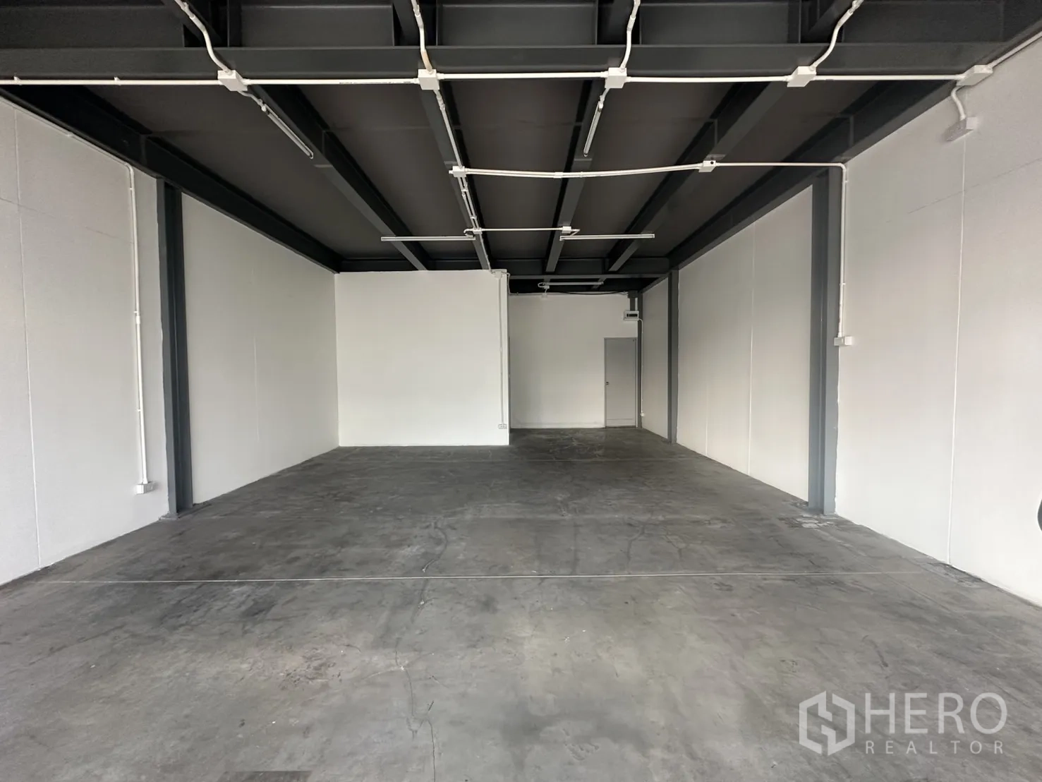 พื้นที่ขายปลีก ให้เช่า - พื้นที่ทรงลึกผนังสีขาว พื้นคอนกรีต พร้อมเดินท่อไฟและโคมไฟลอย