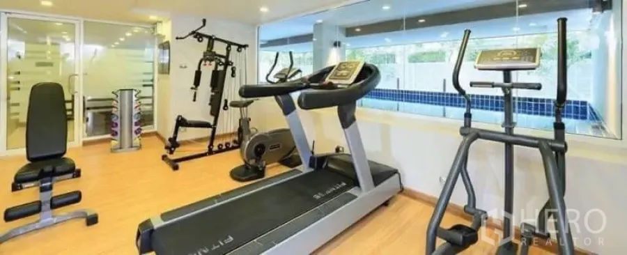 Condominium for rent in Watthana, Bangkok - Condo fitness room with treadmills, elliptical, weight station and a window looking onto the pool.