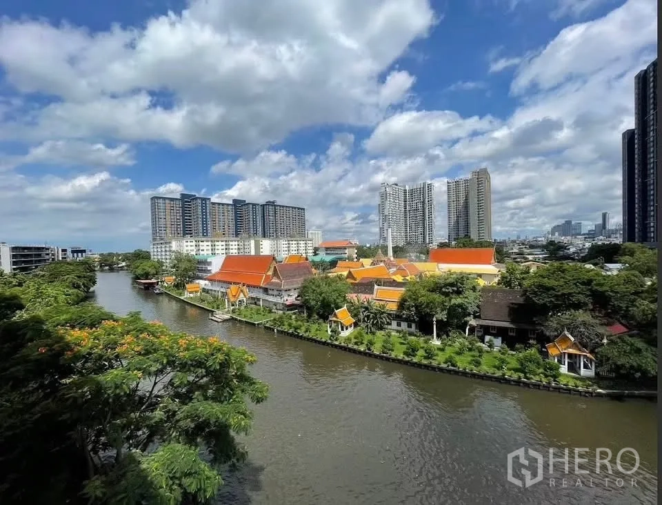 คอนโด for rent in Watthana, Bangkok - มุมสูงเห็นคลองและอาคารหลังคาสีส้มแบบดั้งเดิมพร้อมคอนโดสมัยใหม่ด้านหลัง