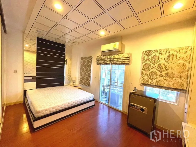 Townhouse for rent in Saphan Sung, Bangkok - Master bedroom with balcony access, large windows, air conditioner and a personal safe.