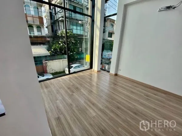 Home Office for sale in Wang Thonglang, Bangkok - Corner workspace with full-height glass walls and wood floors facing the city street.