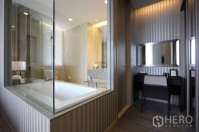 Condominium for rent in Watthana, Bangkok - Master bathroom featuring a glass-walled soaking tub beside vanity and toilet.