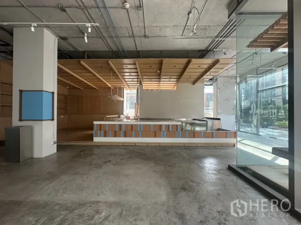 零售空间 出租 - 一层商铺内部，木质吊顶、服务吧台与落地玻璃门面