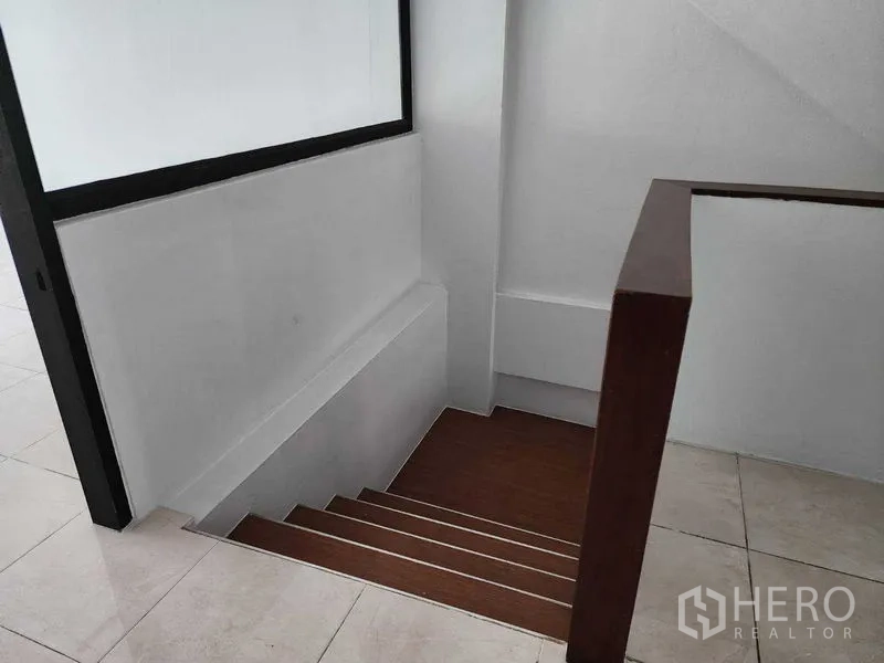 店屋 出租在Khlong Toei, Bangkok - 室内木质楼梯与白色墙面，连接上下楼层。