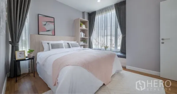 Detached House for sale in Lam Luk Ka, Pathum Thani - Bright guest bedroom with large corner windows, soft bedding and built-in shelving.