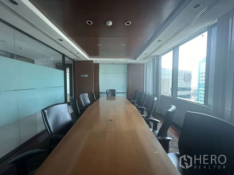 Office Space for rent in Khlong Toei, Bangkok - Boardroom with long wooden table beside glass partitions and windows.