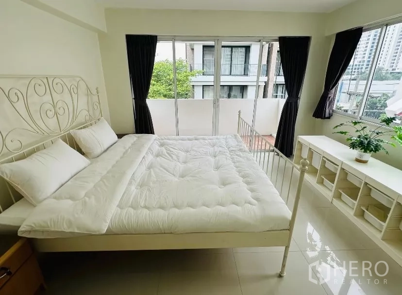 บ้าน ให้เช่า - ห้องนอนเตียงขาว หน้าต่างมุม และประตูกระจกออกสู่ระเบียง.