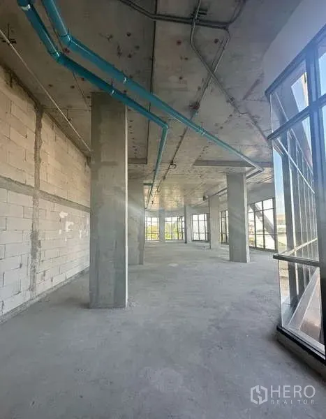 零售空间 出租在Phra Khanong, Bangkok - 毛坯零售空间，高挑层高，混凝土柱与蓝色管线，四周落地玻璃。