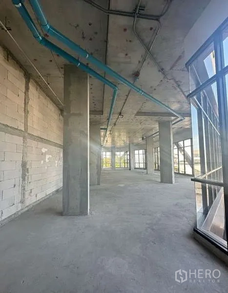 零售空间 出租在Phra Khanong, Bangkok - 毛坯零售空间，高挑层高，混凝土柱与蓝色管线，四周落地玻璃。