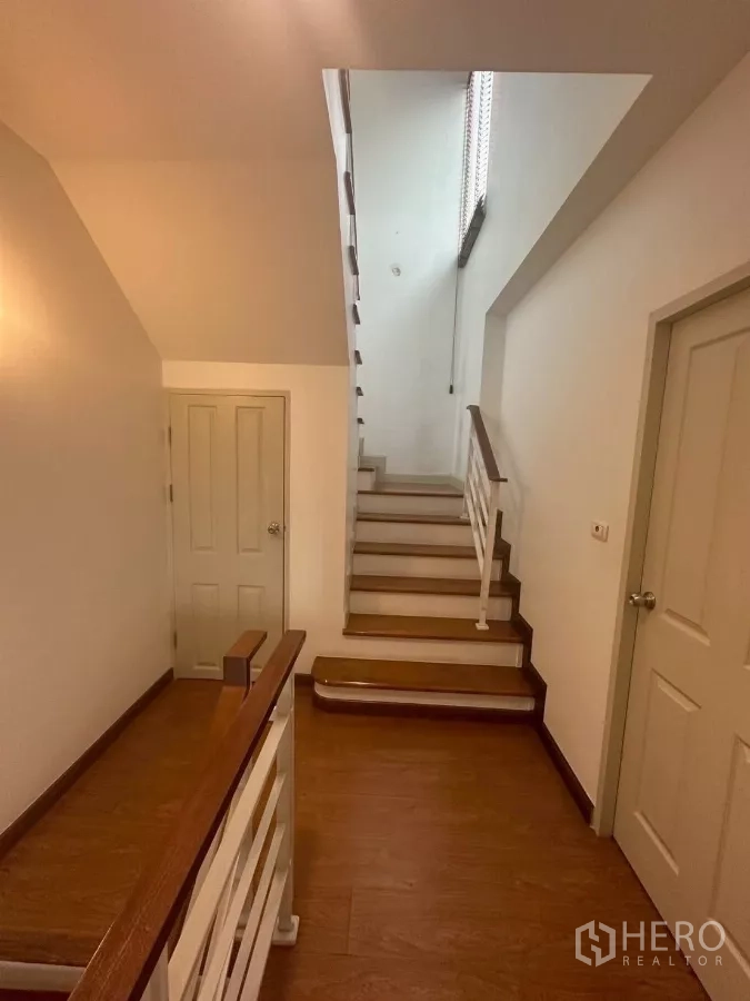 Townhouse for rent in Chom Thong, Bangkok - Stair hall with wooden steps, white railings and doors to rooms.