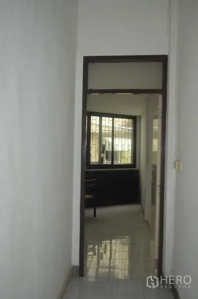 店屋 出租在Khlong Toei, Bangkok - 狭长走廊，白色瓷砖地面，通向带窗的明亮房间。