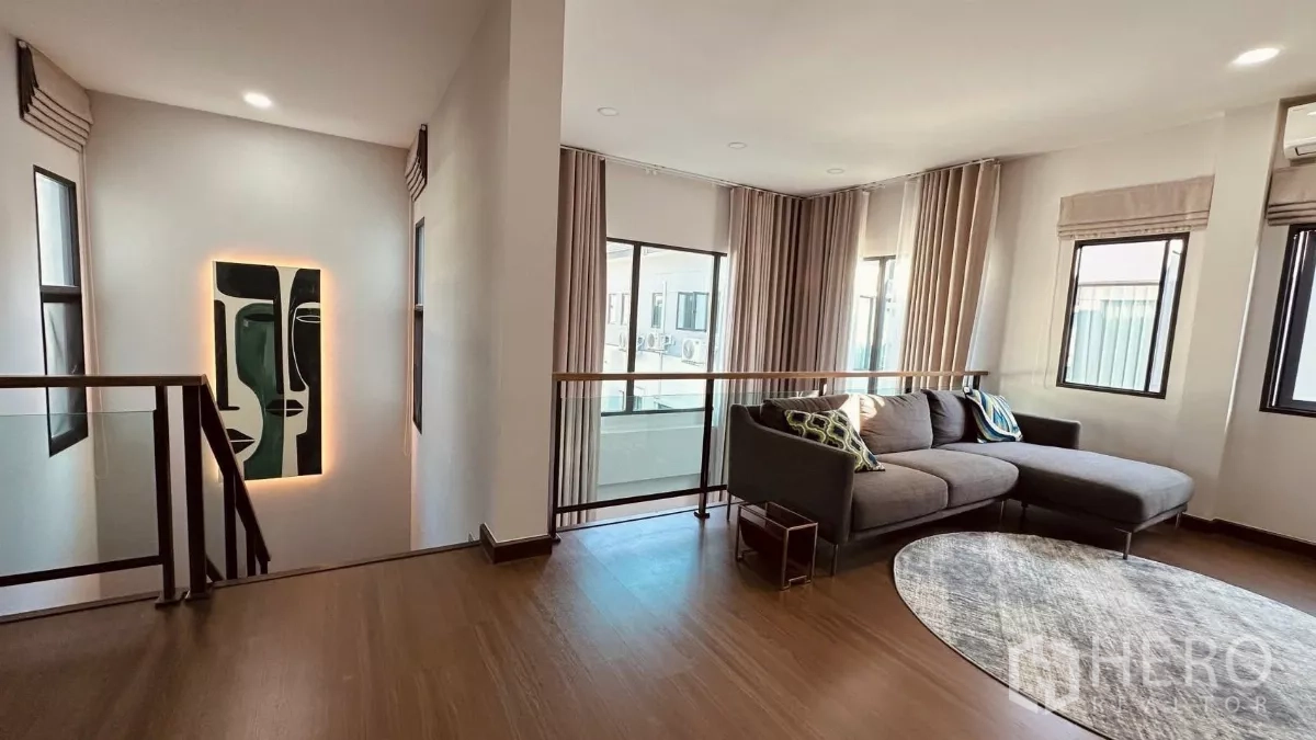 Detached House for rent in Bang Phli, Samut Prakan - Second‑floor landing with a corner sofa and wraparound windows with curtains.