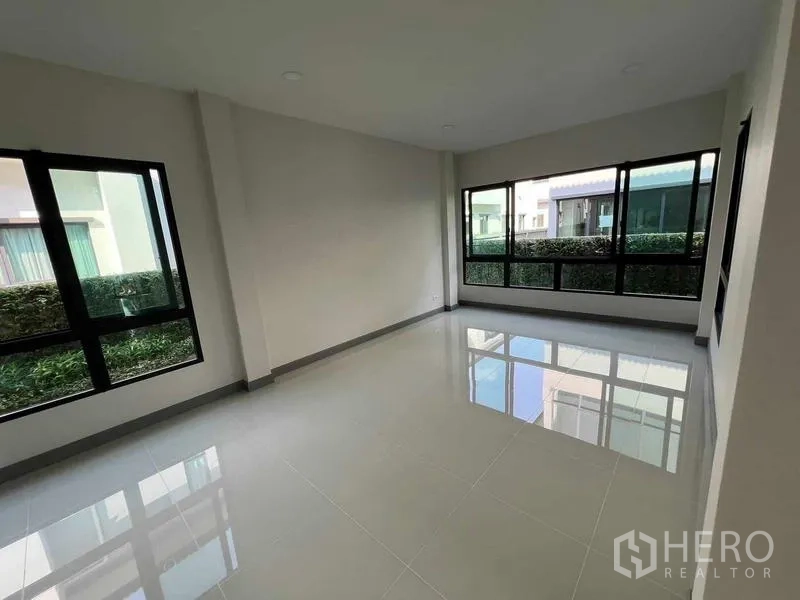 Detached House for rent in Khlong Sam Wa, Bangkok - Light-filled ground-floor room with glossy tile flooring and corner windows.