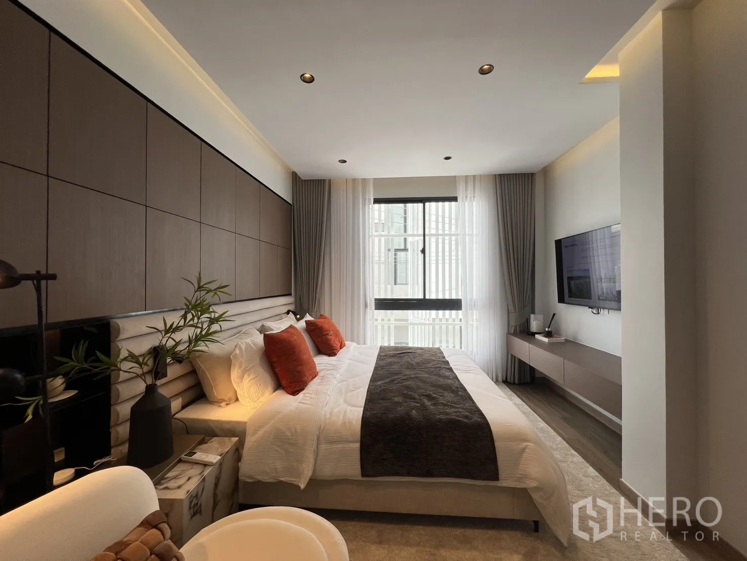 Townhouse for rent in Mueang Samut Prakan, Samut Prakan - Master bedroom with wall-mounted TV, sheer curtains, and bright natural light.