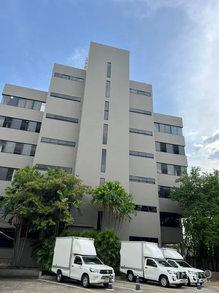 Office Space for rent in Mueang Samut Prakan, Samut Prakan - Mid‑rise office building facade with parking area and delivery trucks.
