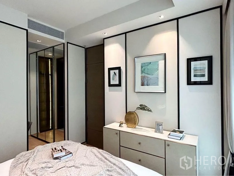 Condominium for rent in Pathum Wan, Bangkok - Bedroom corner with built-in dresser, framed artwork and soft recessed lighting.
