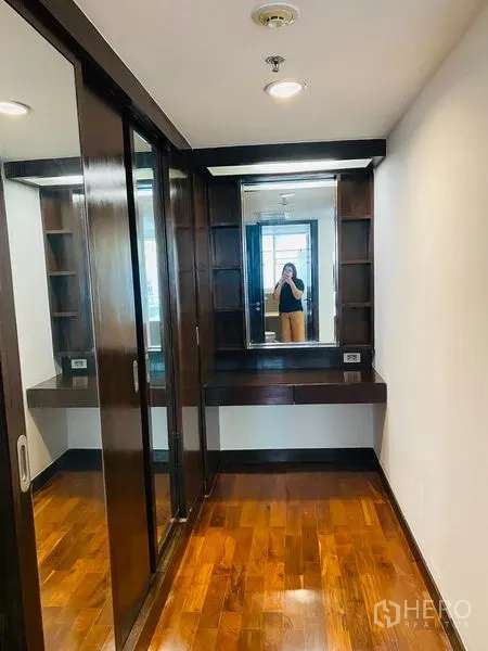 Condominium for rent in Watthana, Bangkok - Walk-in closet featuring mirrored sliding wardrobes and a dressing vanity with shelving.
