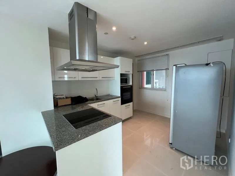 Condominium for rent in Watthana, Bangkok - Modern kitchen with granite counters, island cooktop and stainless hood.