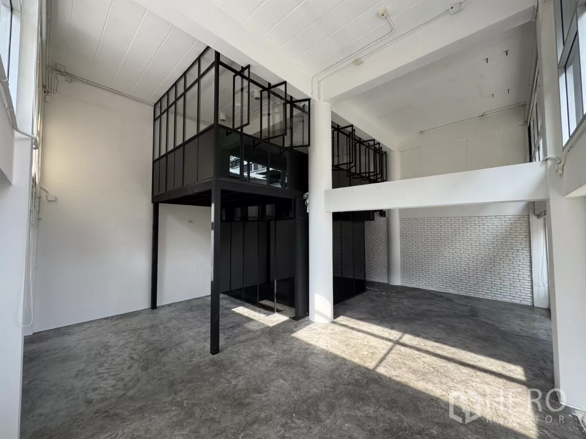 店屋 出租在Wang Thonglang, Bangkok - 挑高展示区，水泥地面、黑框夹层与白色砖墙。