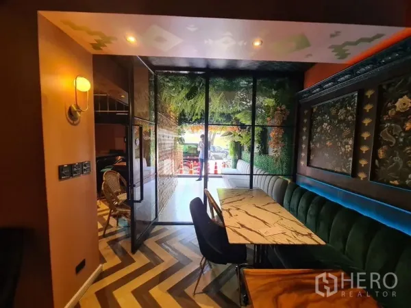 零售空间 出租在Bang Rak, Bangkok - 玻璃门旁室内座位，大理石桌、绿色长椅与几何地板。