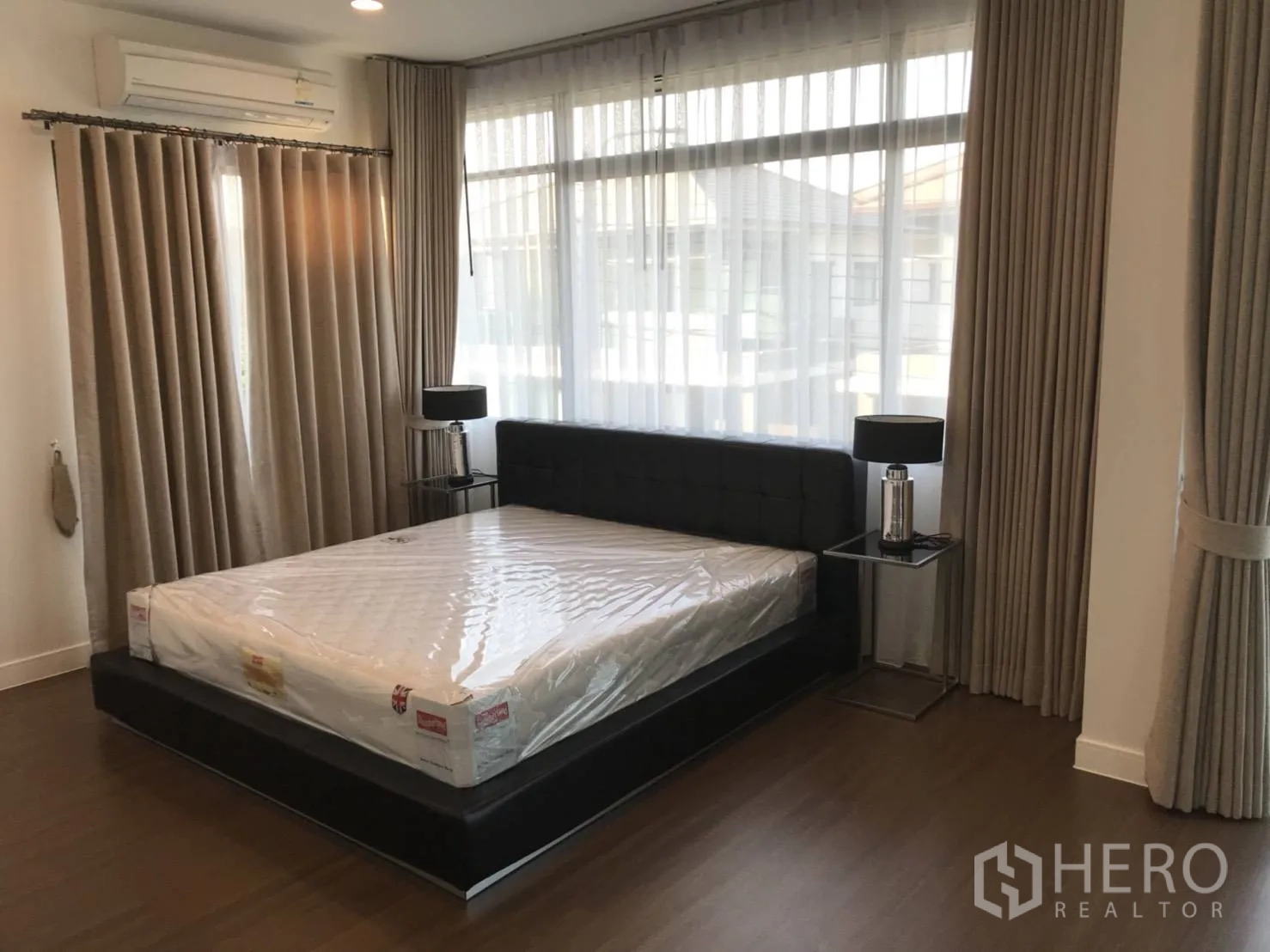 Detached House for rent in Bang Kapi, Bangkok - Master bedroom with double bed, bedside tables, wide windows and wood flooring.