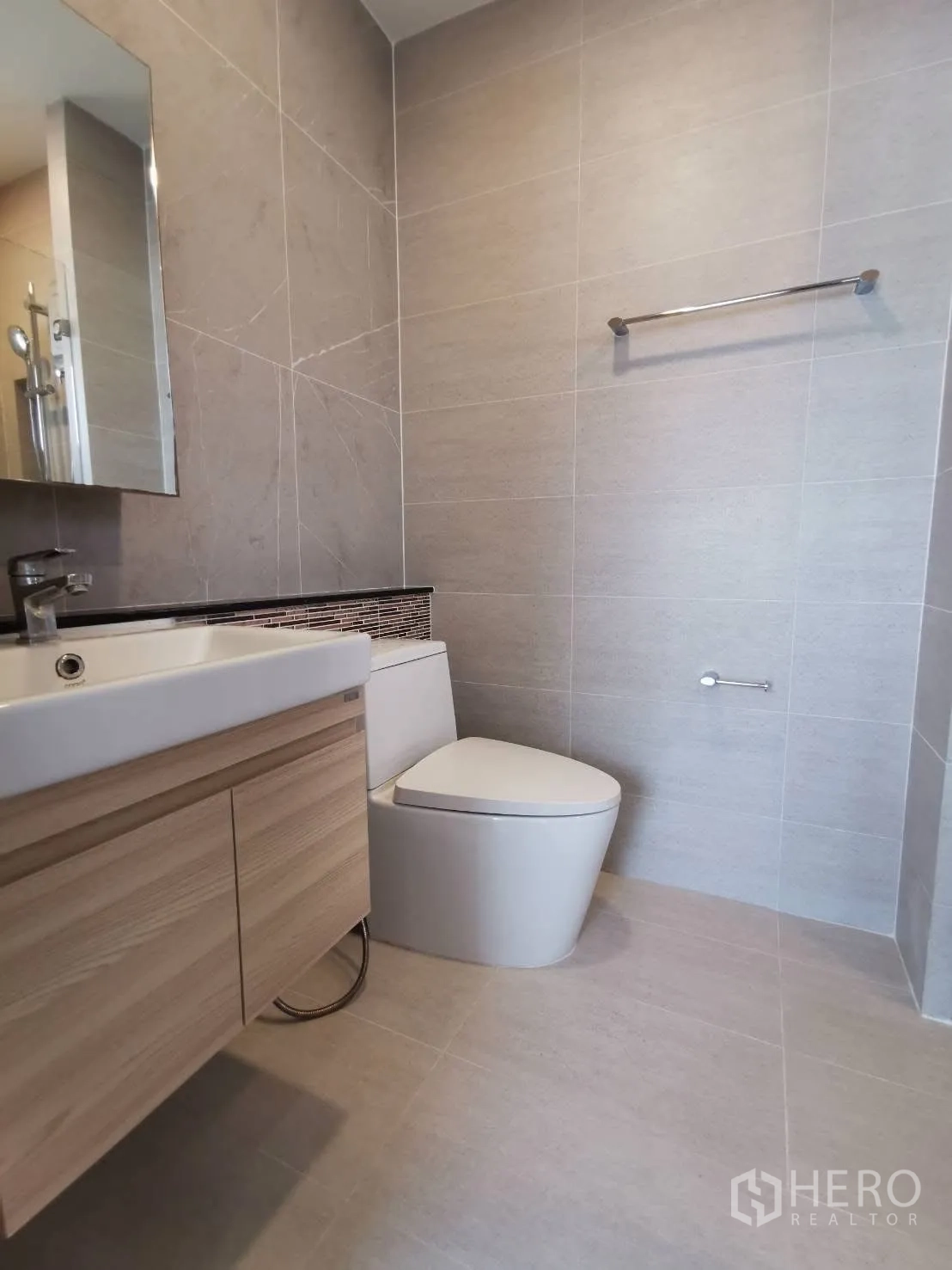 Detached House for rent in Bang Phli, Samut Prakan - Modern bathroom with wall-mounted vanity, mirror, and toilet finished in neutral beige tiles.