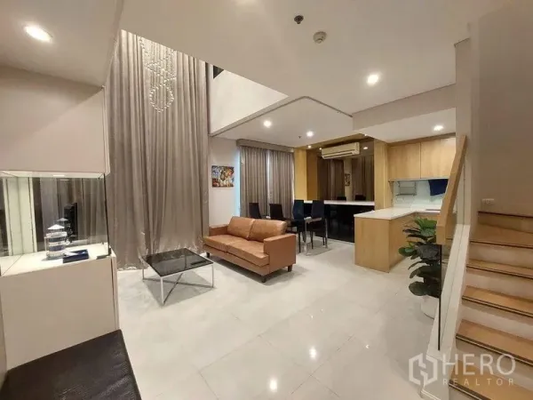 คอนโด ให้เช่าหรือขายในRatchathewi, Bangkok - ห้องนั่งเล่นคอนโดดูเพล็กซ์ เพดานสูงสองชั้น โคมระย้าคริสตัล ครัวเปิด และบันได