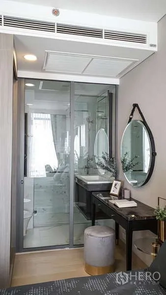 Condominium for sale in Khlong Toei, Bangkok - Work vanity next to a glass-enclosed bathroom with modern fixtures and illuminated mirror.