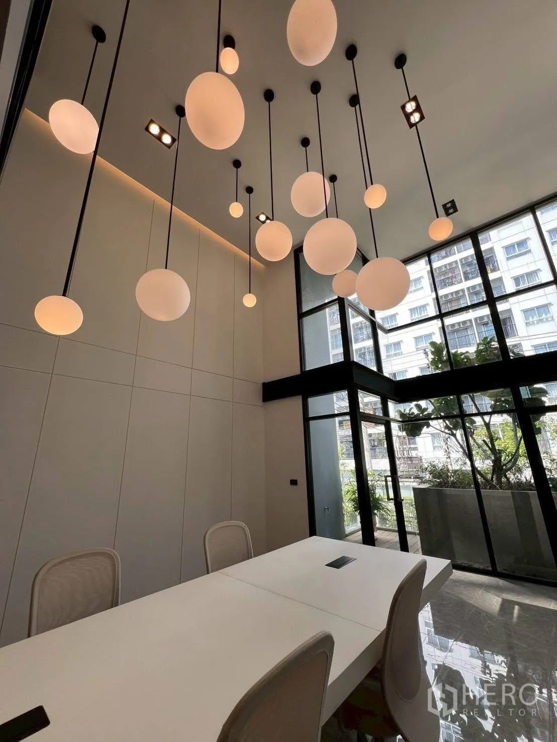 Home Office for rent or sale in Mueang Samut Prakan, Samut Prakan - Meeting area with globe pendant lights and tall windows opening to a patio garden.