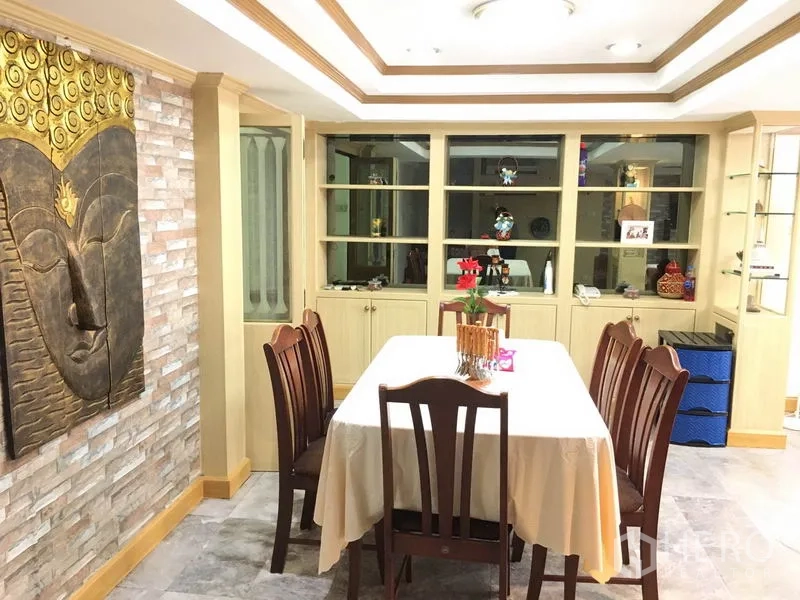 Townhouse for rent in Khlong Toei, Bangkok - Dining room close‑up featuring Buddha wall art, recessed lighting and glass‑front shelving.