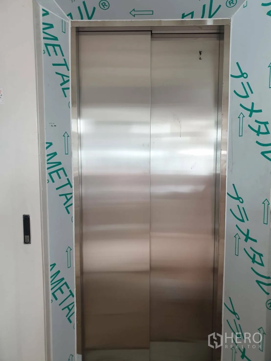 Office Space for rent or sale - Stainless-steel passenger elevator with protective wrap in the lobby.
