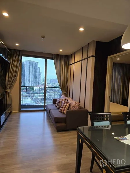 Condominium for rent - Lounge with balcony access and doorway to bedroom, evening city outlook.