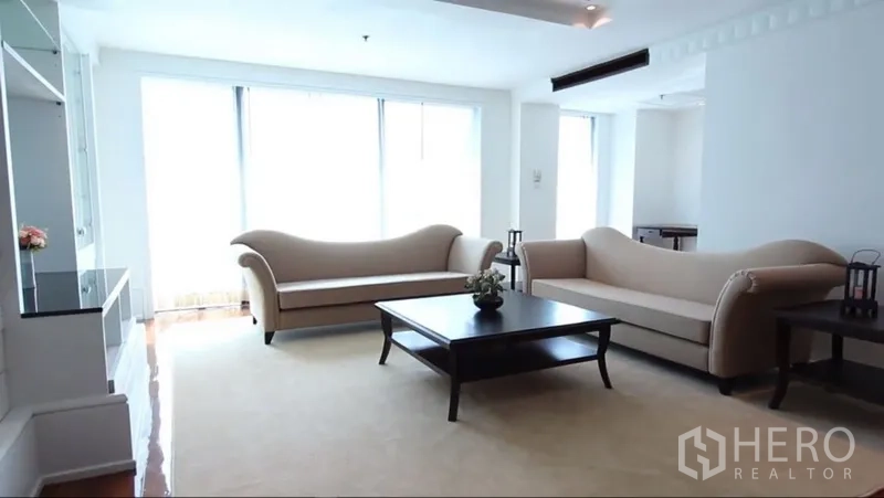 房间 出租在Khlong Toei, Bangkok - 采光充足的客厅，双沙发、茶几与大面积窗户。