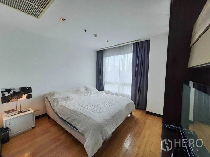 Condominium for rent in Yan Nawa, Bangkok - Primary bedroom with large bed, window and blackout curtains.