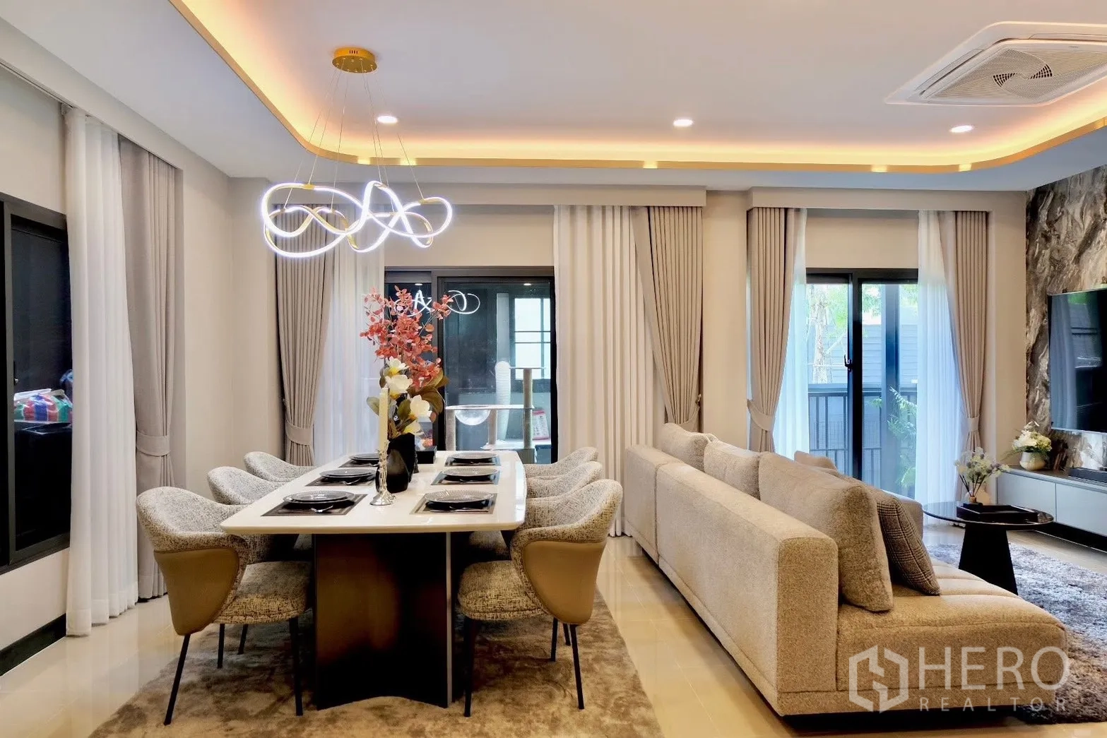 Semi-detached House for sale in Prawet, Bangkok - Dining table and lounge area with cove lighting and TV wall.