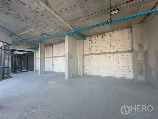 零售空间 出租在Phra Khanong, Bangkok - 开放式毛坯商铺，混凝土立柱、砌块墙与外露管线，旁见楼梯。