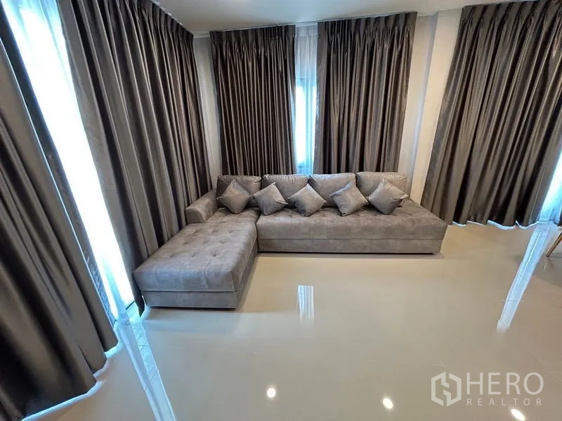 Detached House for rent in Bang Phli, Samut Prakan - Corner sofa with multiple cushions surrounded by full-length curtains.